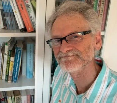 Dr Jon Gamble taking a selfie in front of a bookshelf 