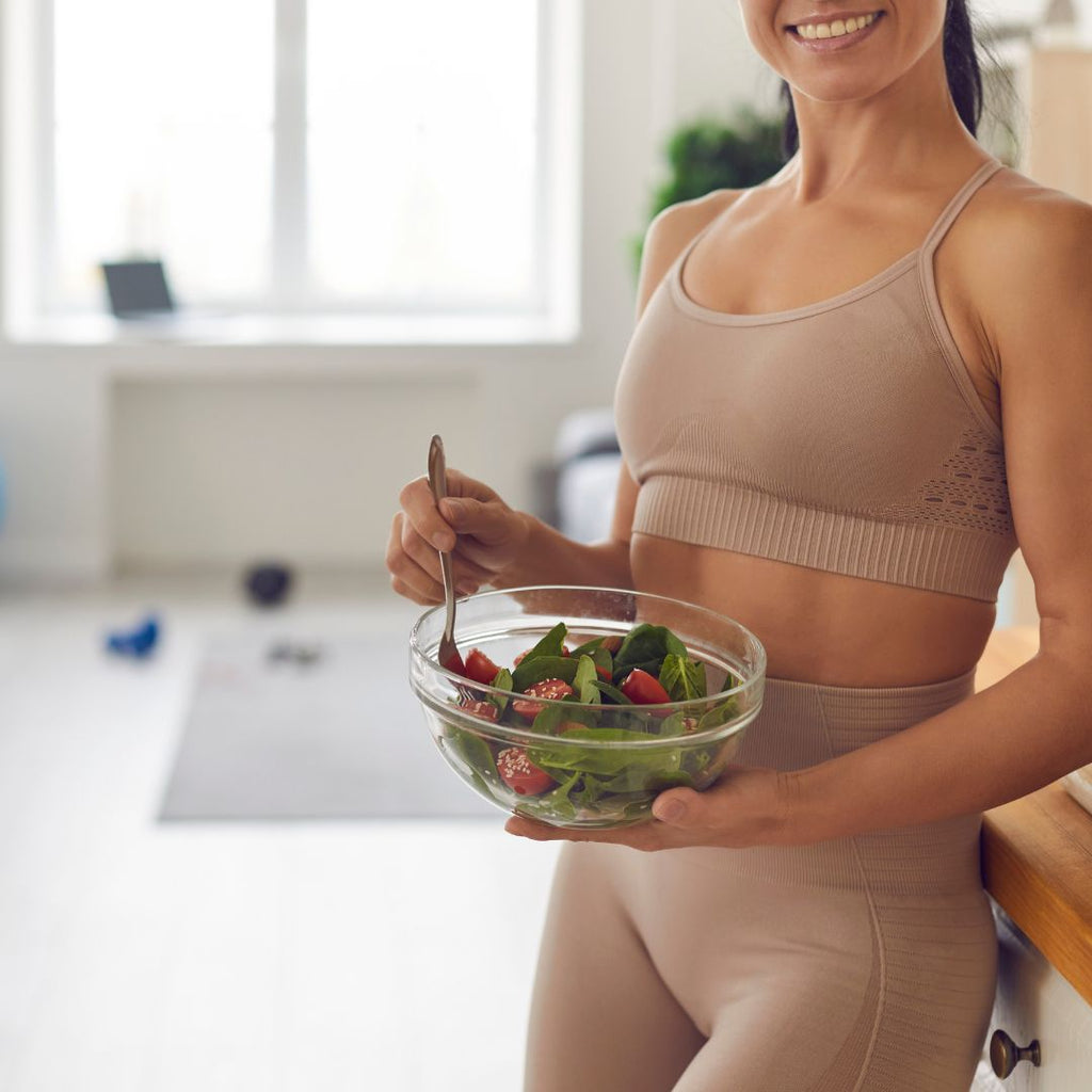 A lady in activewear holding a salad